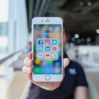 Woman holding Apple iPhone 6S Rose Gold with icons of social media on screen. Social media are most popular tool. Smartphone life style. Starting social media app.